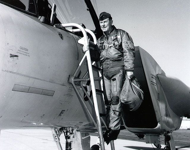 Chuck Yeager standing on ladder on outside of aircraft.