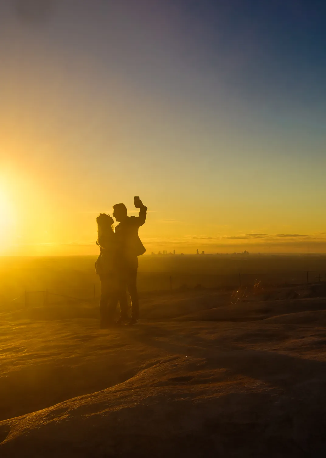 15 - A couple takes a selfie with the skyline of Atlanta barely visible in the background as the sun begins to set.