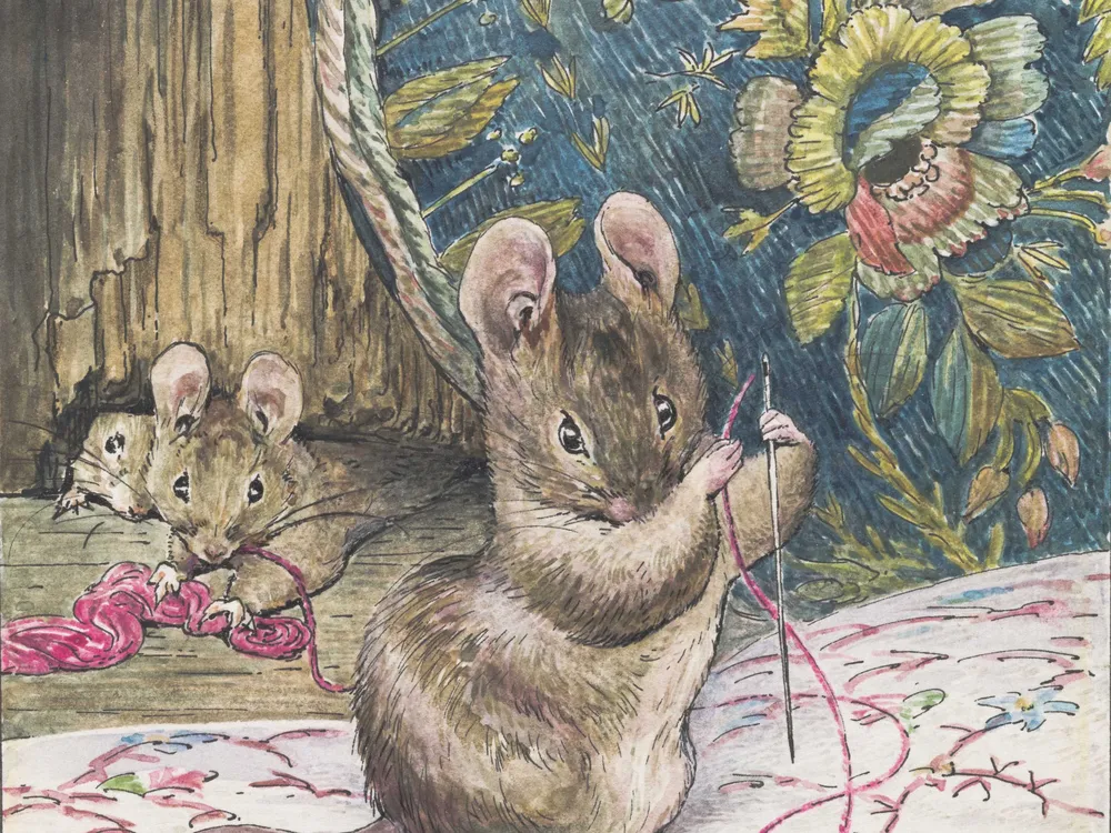 A brown mouse holds a needle and piece of pink thread and works on a delicate embroidery pattern of pink, blue and green flowers on white cloth, while two mice look on behind