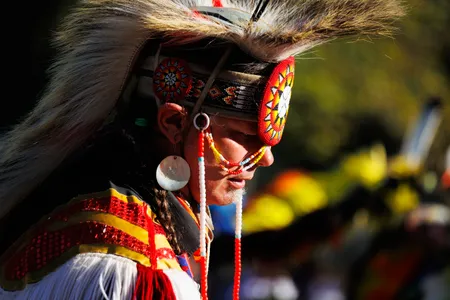 A member of the Muscogee Creek Nation pauses at the edge of the dance circle in traditional regalia at an event in Nashville.