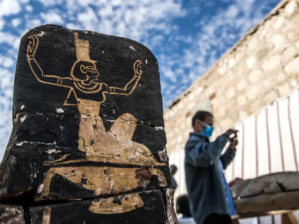 Tourist stands next to wooden coffin unearthed at Saqqara