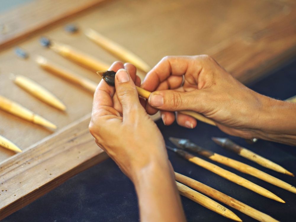 Pair of hands holding an arrowhead on wooden dowel