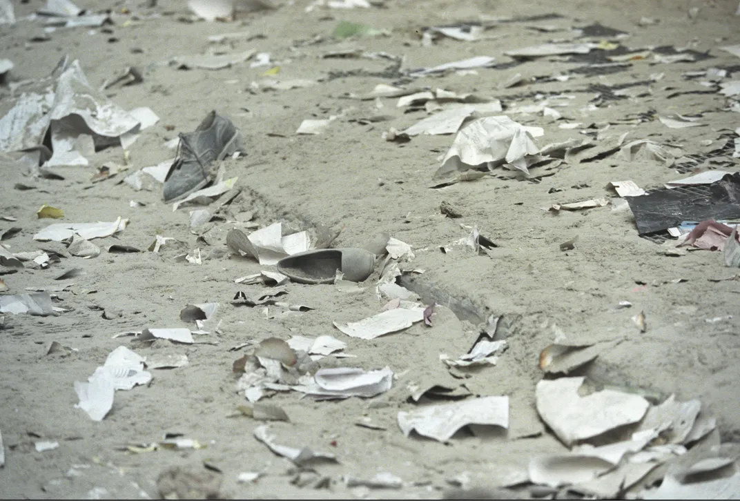 A shot of the ground, covered in thick gray ash, paperwork and discarded shoes--a woman's heel, a man's loafer--that had fallen from the towers or been left behind