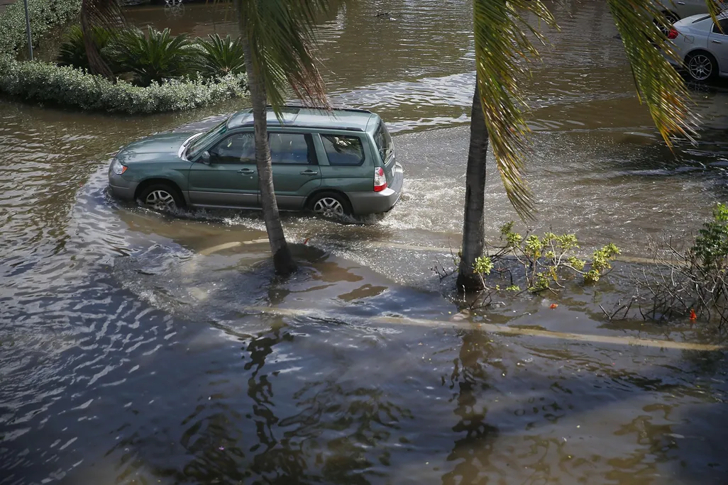 A vehicle drives through flooded streets caused by the combination of the lunar orbit which caused seasonal high tides and what many believe is the rising sea levels due to climate change on September 30, 2015 in Fort Lauderdale, Florida