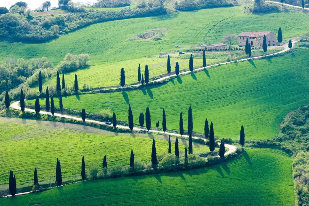 The quintessential Tuscan countryside, replete with rolling hills, cypress trees, and farmhouses