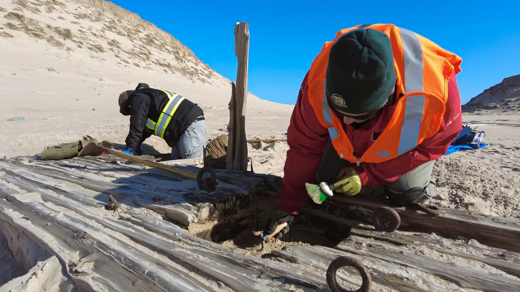 Archaeologists bent over shipwreck timbers