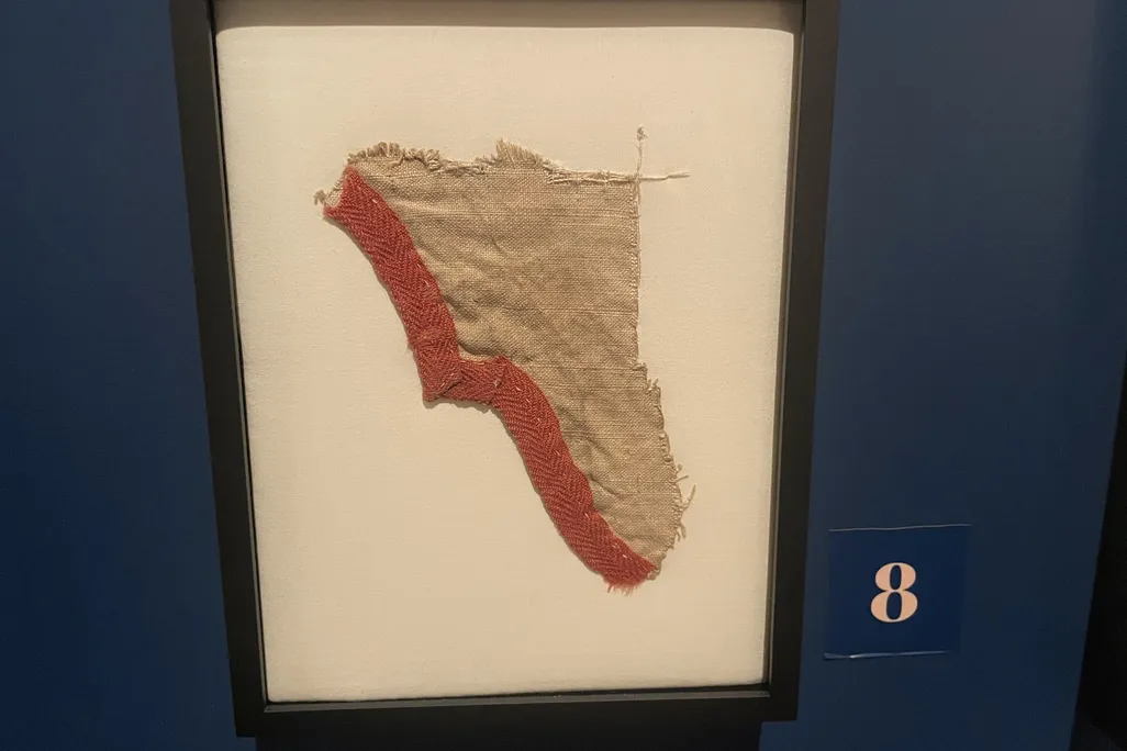 Scrap of old fabric in a frame hanging on a dark blue wall