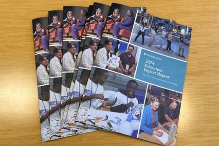 Seven copies of the Impact Report are fanned out on a wood table.