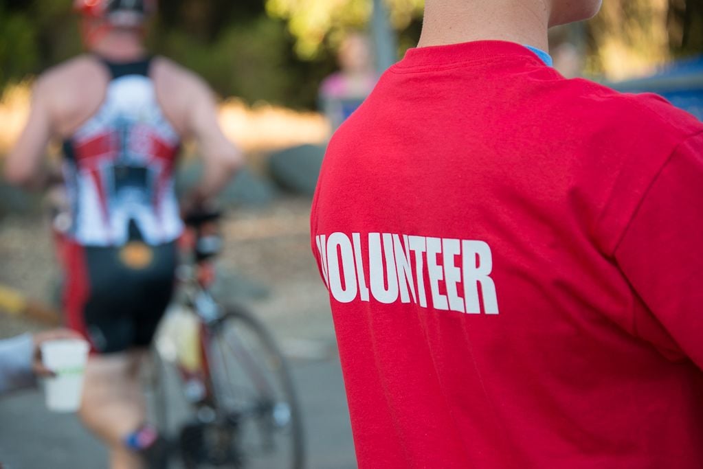 A red-shirted volunteer is on hand to help participants in a triathlon ...