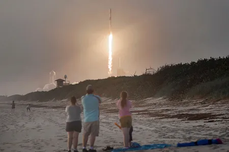 Spectators watch from Canaveral National Seashore as a SpaceX Falcon 9 rocket carrying 60 Starlink satellites launches.