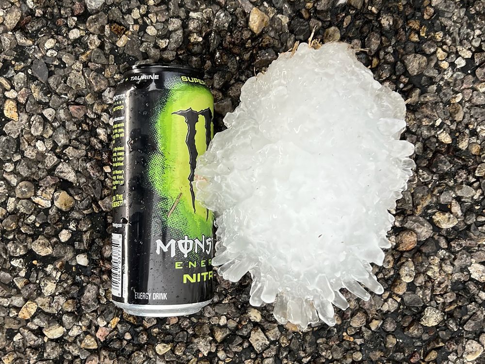 a large hail stone on the ground next to a monster energy can; it is taller than the can