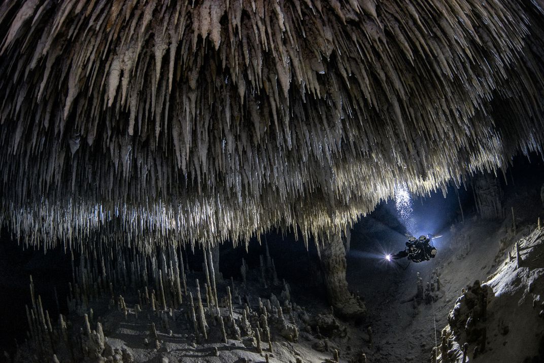 An image of an underwater cave with thousands of stalactites piercing the water