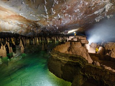Cavers stand amongst large gour pool walls and unique raft cone formations inside Hang Va.