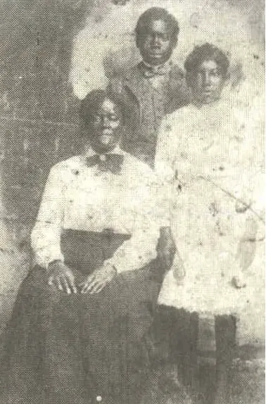 Sarah Carrier (seated at left) and her children Sylvester (standing at left) and Willie (standing at right)