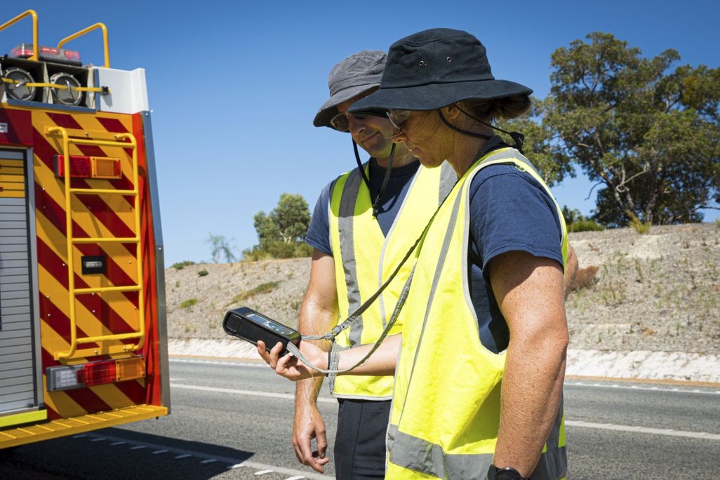 people in yellow vests look at a radiation detector