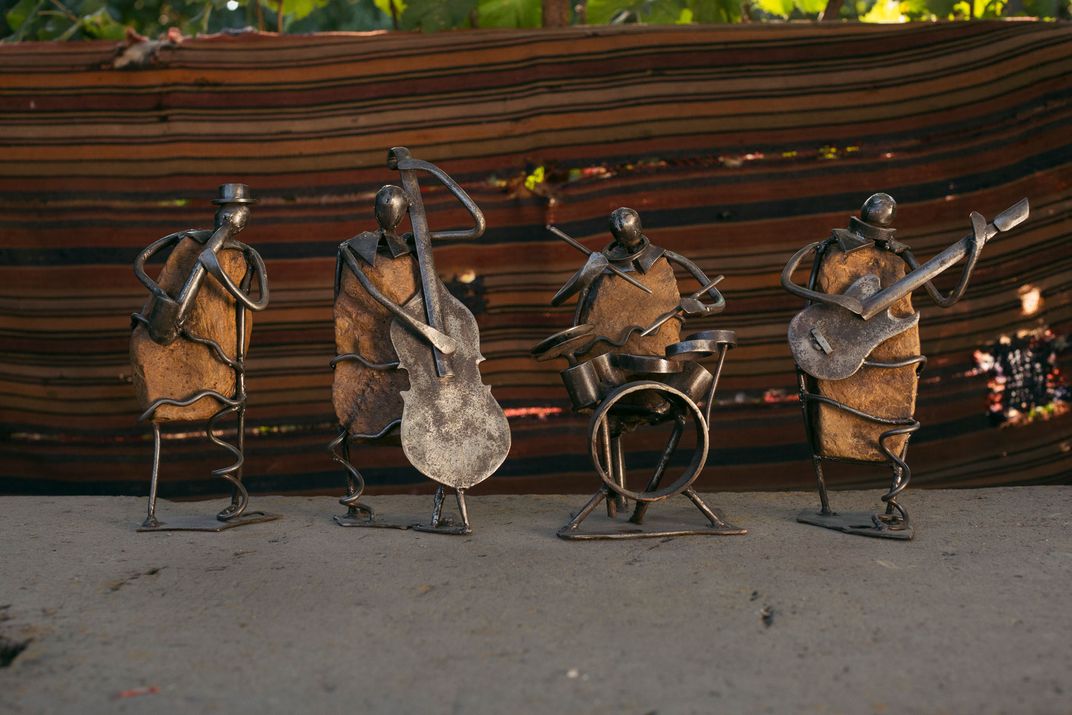 Four metal sculptures of human figures playing instruments are positioned next to each other.