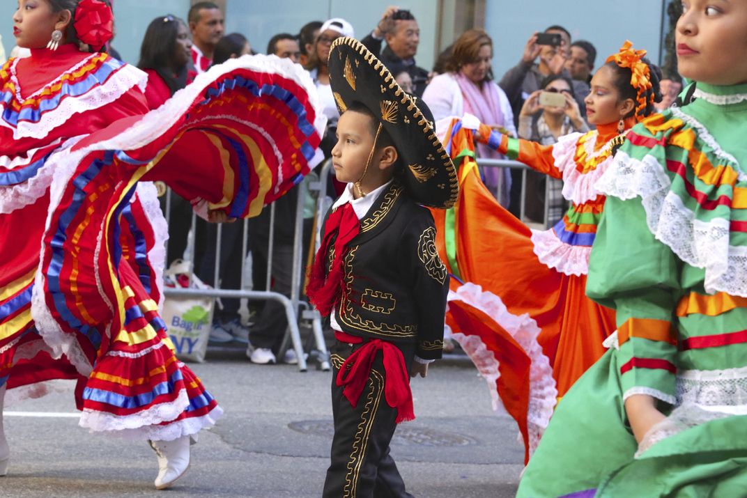 a boy wears a sombrero  in a parade.