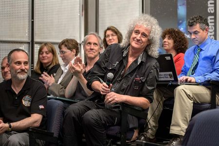 Astrophysicist Dr. Brian May is recognized during a July 17, 2015 New Horizons science briefing at NASA Headquarters, Washington, D.C. May spent a long birthday weekend with the science team, attending two morning science plenaries, a meeting with the Student Dust Counter group, and working on stereo images of Pluto with the Geology, Geophysics and Imaging (GGI) team.