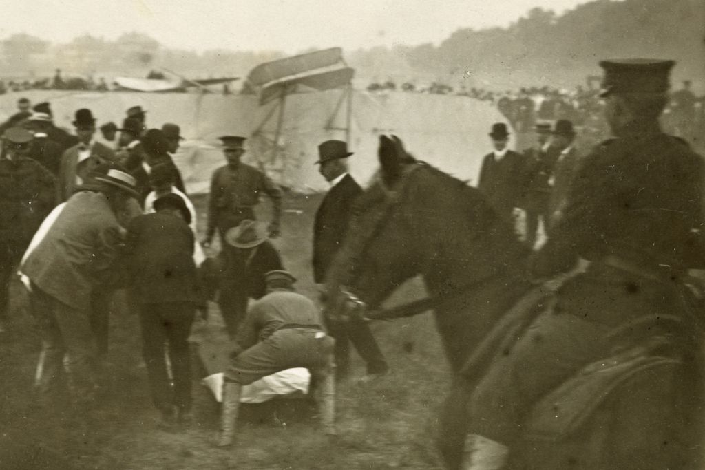 Bystanders crouch over Thomas Selfridge, pulled from the wrecked Wright Model A.