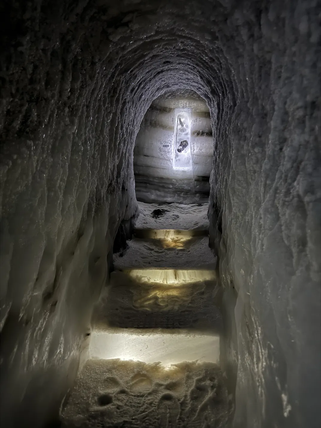 an ice tunnel with steps leads to an artifact on display