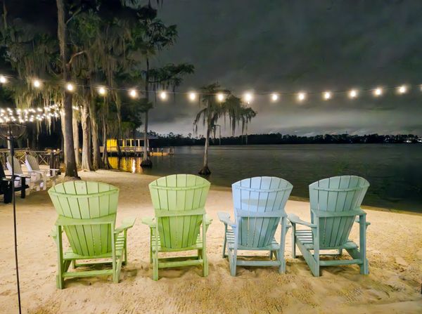 Empty Adirondack Lawn Chairs in the Sand Beach by the Lake at night thumbnail