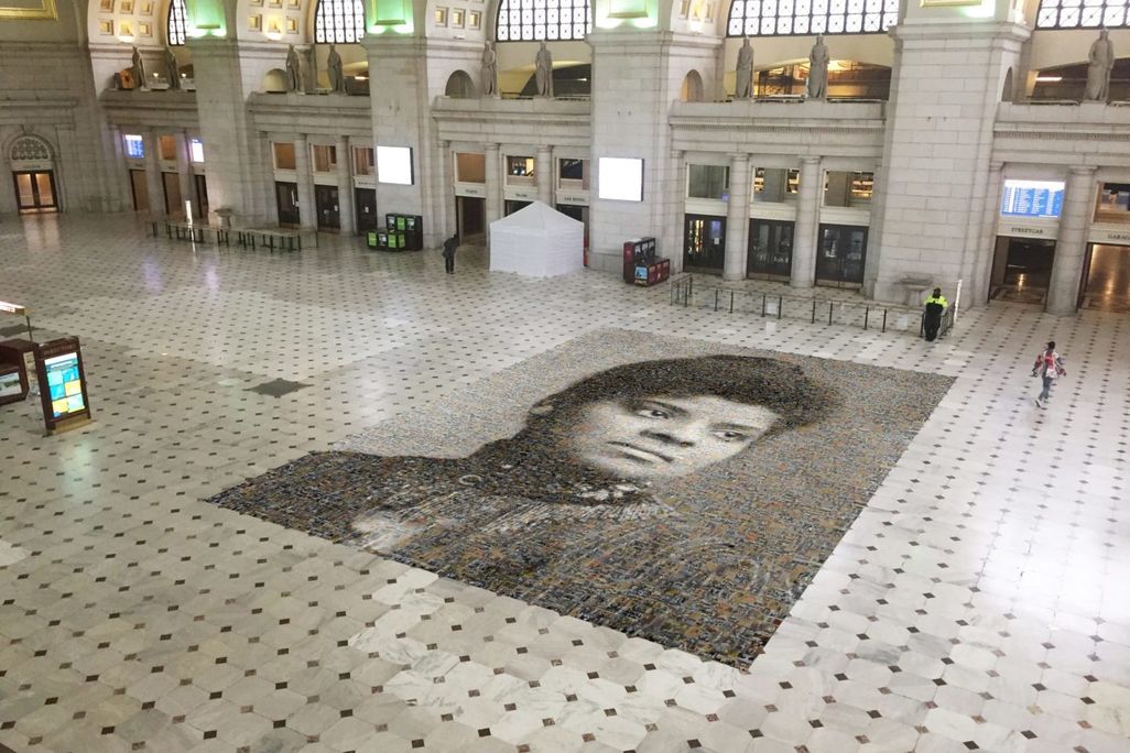An aerial view of the mosaic, with two people walking nearby for scale; the mosaic takes up 1,000 square feet of floor in Union Station. The station is currently mostly empty due to the Covid-19 pandemic.