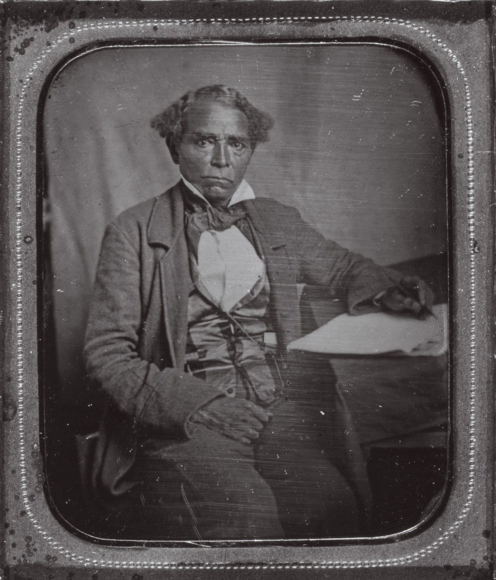 a tintype of man sitting at a table for a portrait