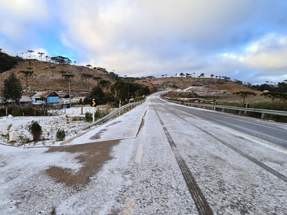 Foto de uma estrada que leva a São Joaquim, Brasil.  A estrada está coberta por uma poeira fofa de neve. 