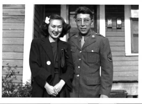 Black and white image of couple standing in front of house