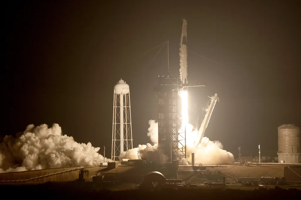 A rocket carrying a spacecraft with four astronauts launches against a night sky