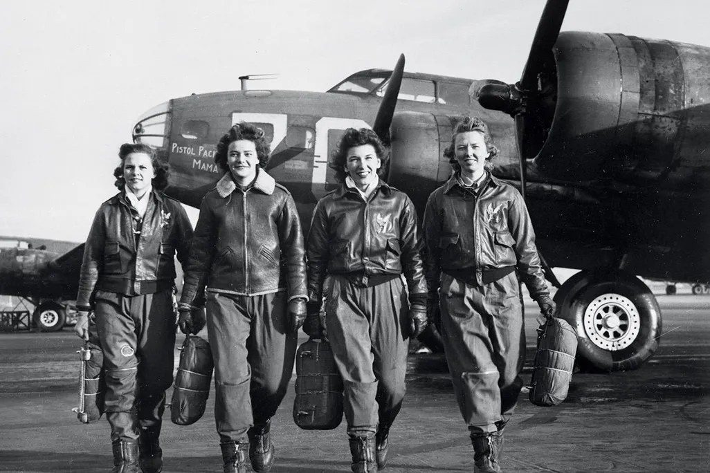 Women Airforce Service Pilots (left to right) Frances Green, Margaret Kirchner, Ann Waldner, and Blanche Osborn pass a line of Boeing B-17s