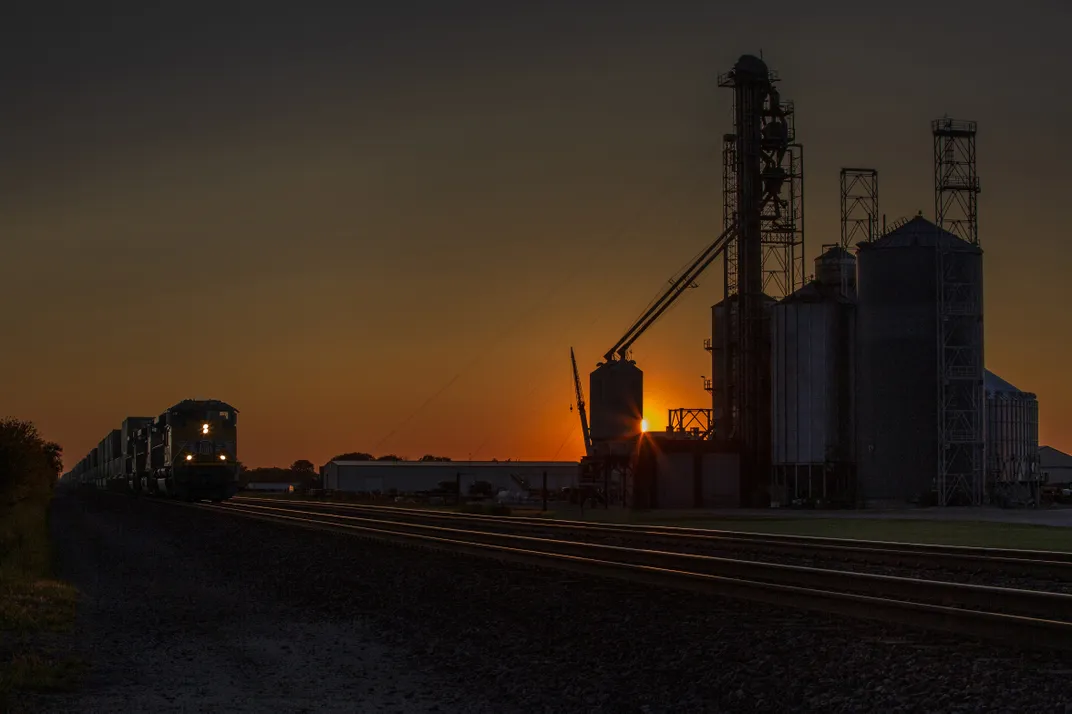 11b - Like cathedrals rising over the vast farming landscape of central Illinois, a series of silos stand at attention at sunset as an eastbound freight train heads toward downtown Chicago.