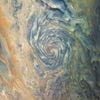 A massive atmospheric vortex on Jupiter is a dizzying swirl of brown, yellow, and green clouds that form a deep tunnel.