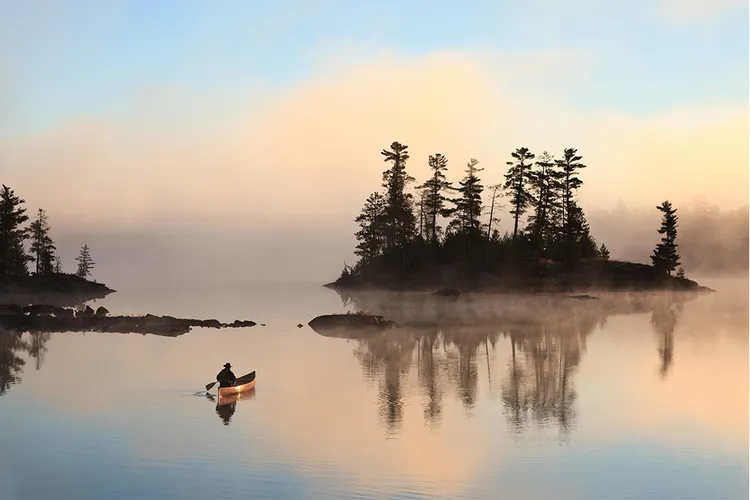 a kayaker on a lake at sunrise or sunset