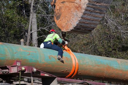 A worker unloads pipe from a truck during construction of the southern portion of the Keystone XL pipeline.