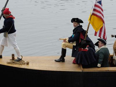 Re-enactors dressed as George Washington and his volunteer Continental Army cross the Delaware River.