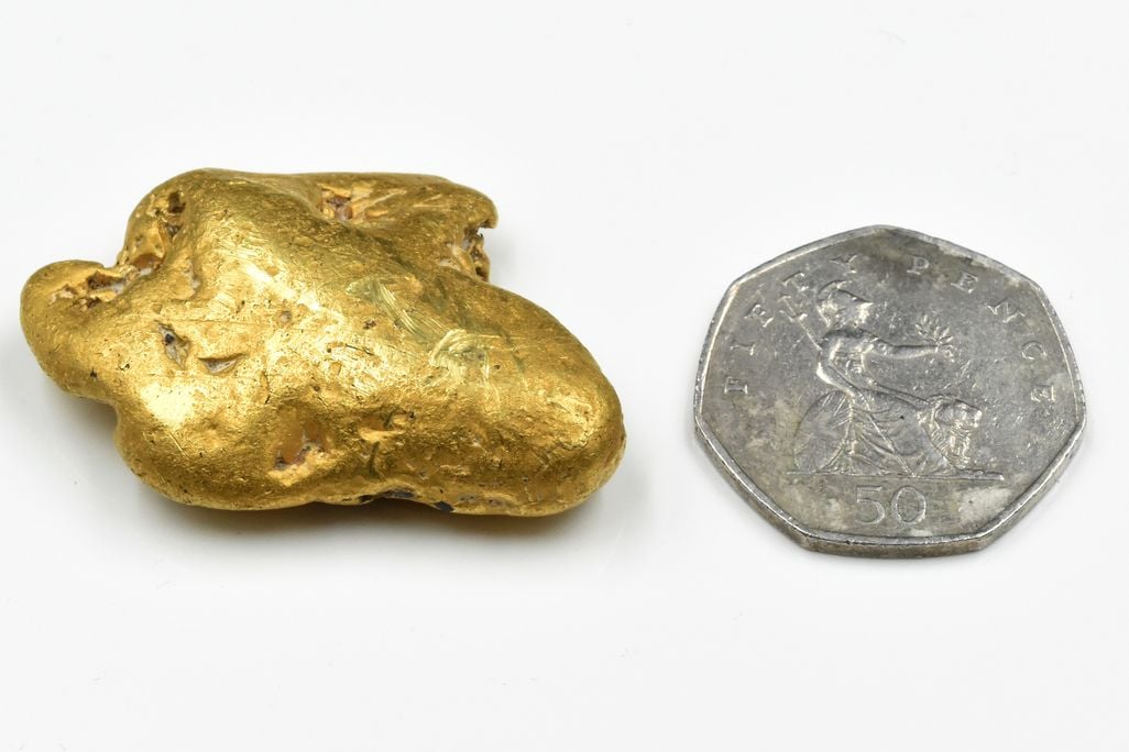 Gold nugget next to coin