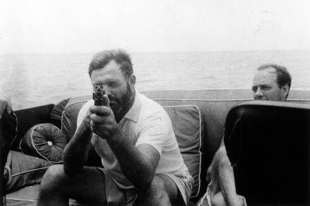 Hemingway led a life of adventure and, sometimes, violence. The author is shown here holding a tommy gun aboard the Pilar in 1935.