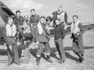 Pilots of No. 19 and No. 616 Squadrons—along with Flash the Alsatian and Rangy the spaniel—pose by a Spitfire. “How should you live if you are 20 and will be dead by the end of the summer?” asks Chaplain Guy Mayfield.