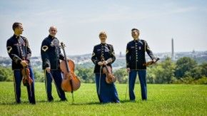 Four musicians with string instruments pose for a photo