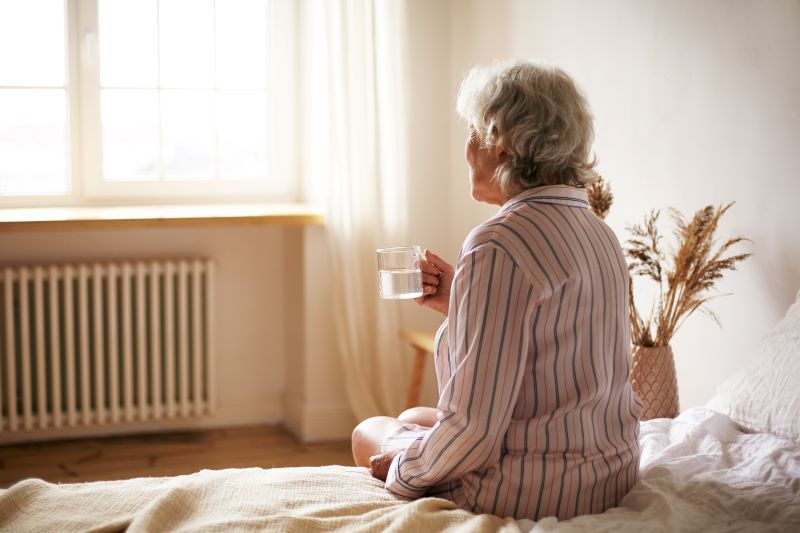 An elderly woman looks out her window