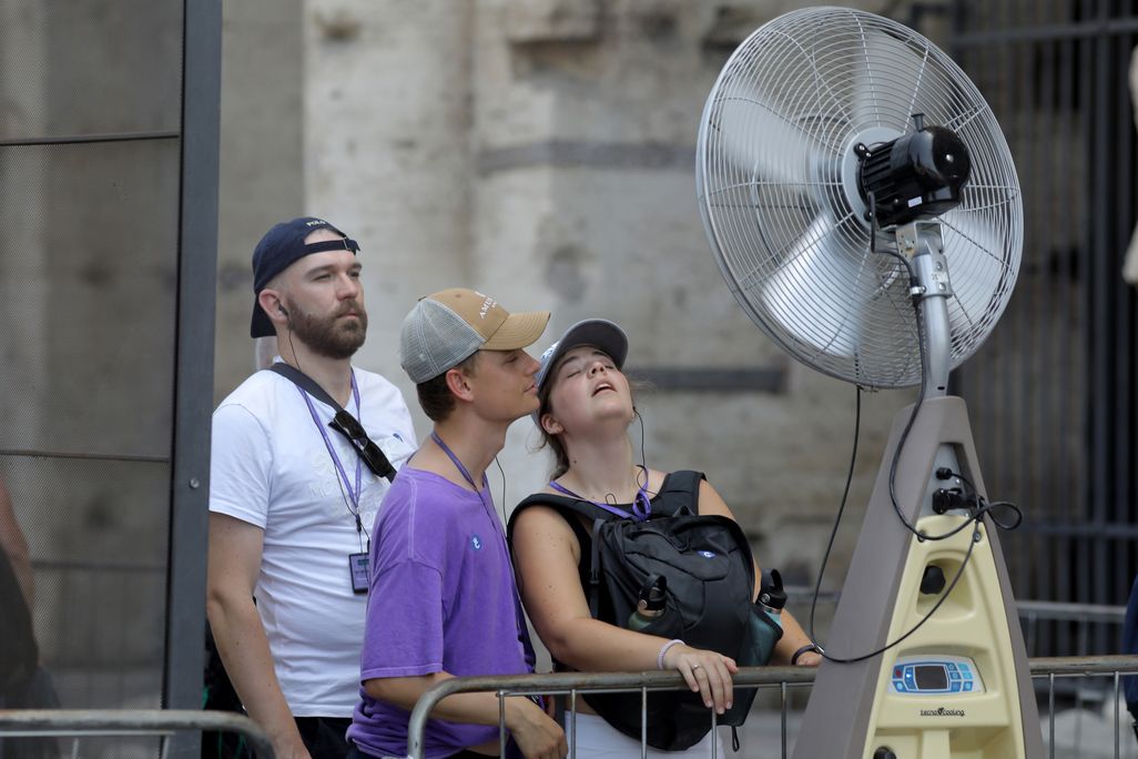 People cool off in front of an outdoor fan