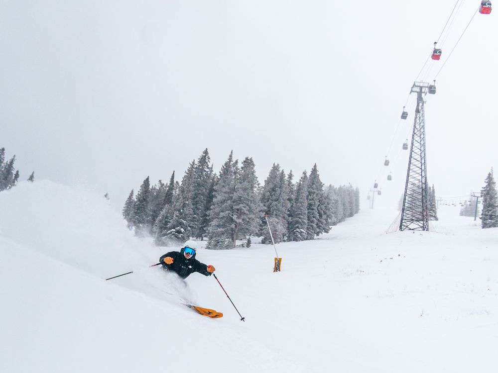 Person skiing on snow with gondola in the background