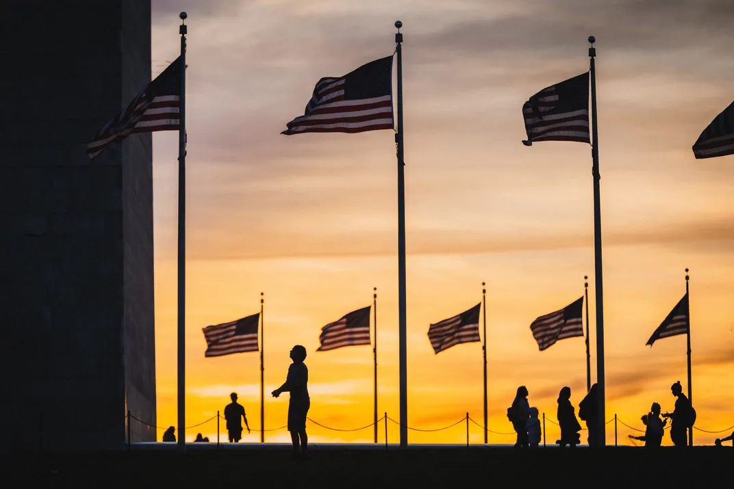 2 - American flags circle the Washington Monument as the setting sun silhouettes nearby tourists.