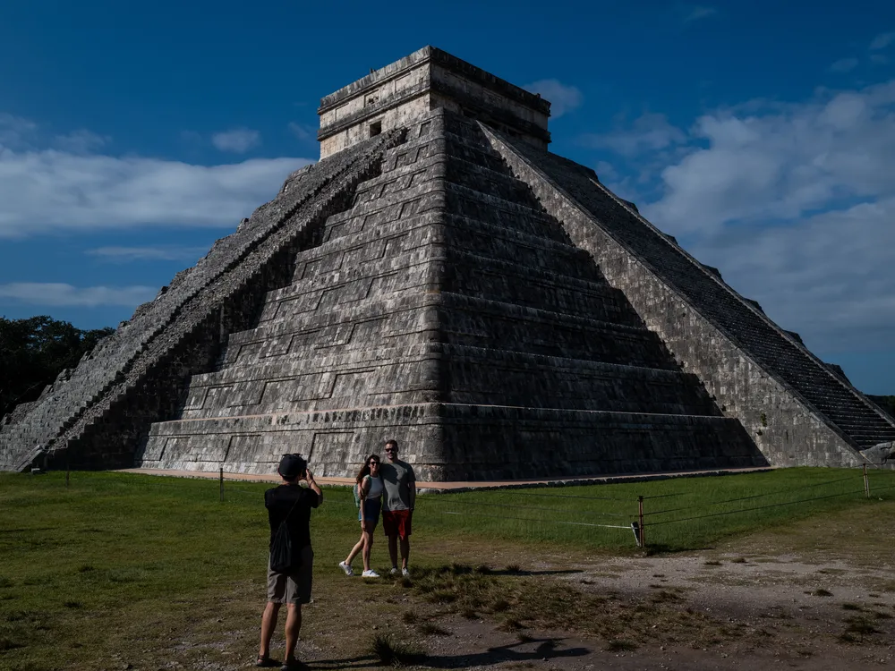 Man and woman posing for photo in front of pyramid-like structure