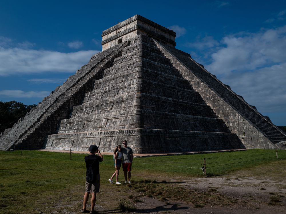 Un hombre y una mujer posan frente a una estructura piramidal.