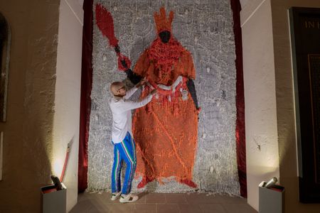 Artist Victor Ehikhamenor posing with his work, Still Standing,&nbsp;a mixed-media depiction of a Benin ruler.
