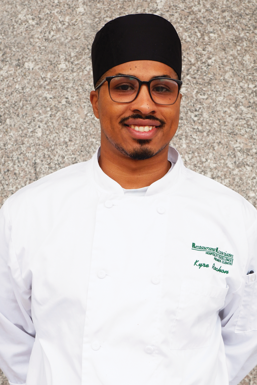 A man dressed in a chef's uniform poses for a portrait