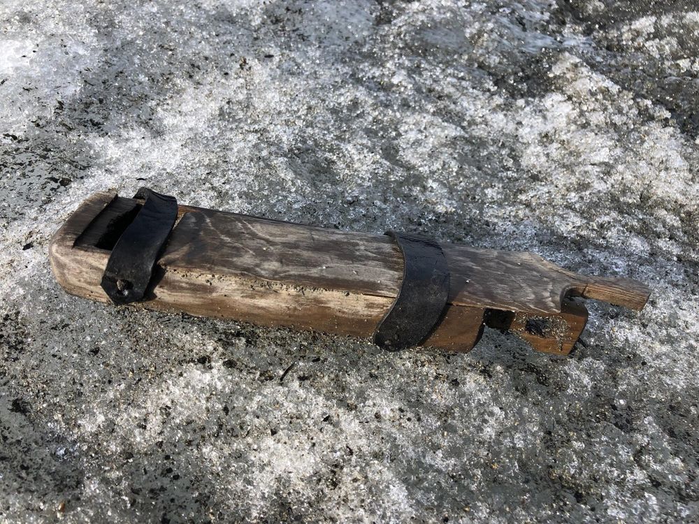 A long rectangular wooden box rests on a rocky surface outdoors