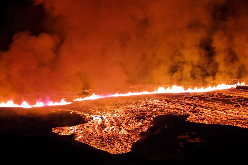 glowing lava erupting from a fissure and spreading across the ground
